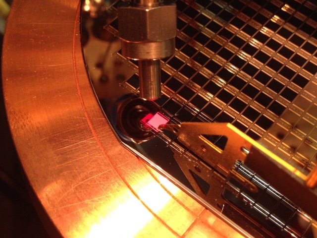 Multi-junction solar cell testing. When electrical current is injected in the solar cell, it emits light – bright red in the case of a GaInP solar cell – that can be collected and analysed with a probe. Devices fabricated at the Fraunhofer Institute of Solar Energy Systems, Germany (http://www.ise.fraunhofer.de).