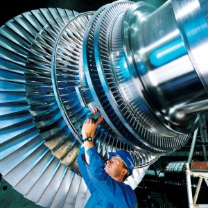 A worker installing a turbine blade on a steam turbine rotor being assembled in a Siemens factory in Germany by Siemens Pressebild