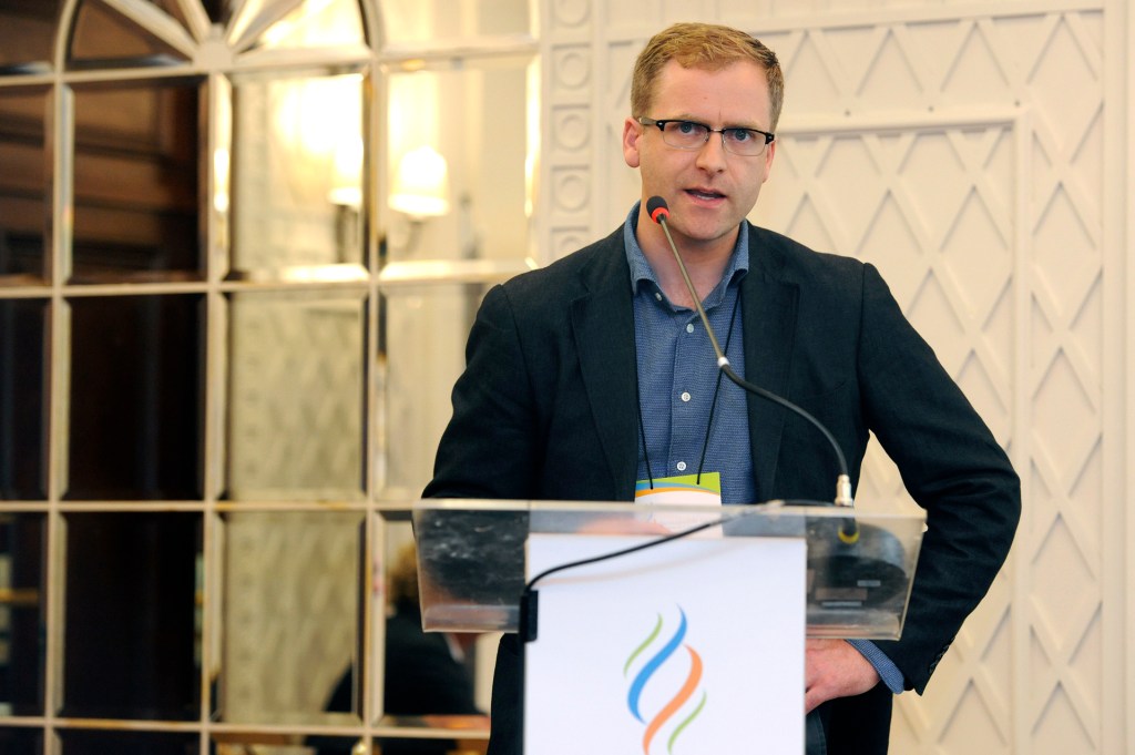 Dr Jamie Speirs standing at a podium.